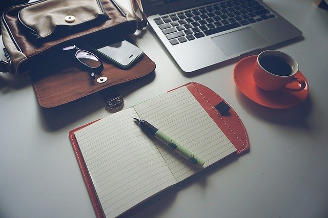 decorative image of desk with bag, notebook, pc and coffee